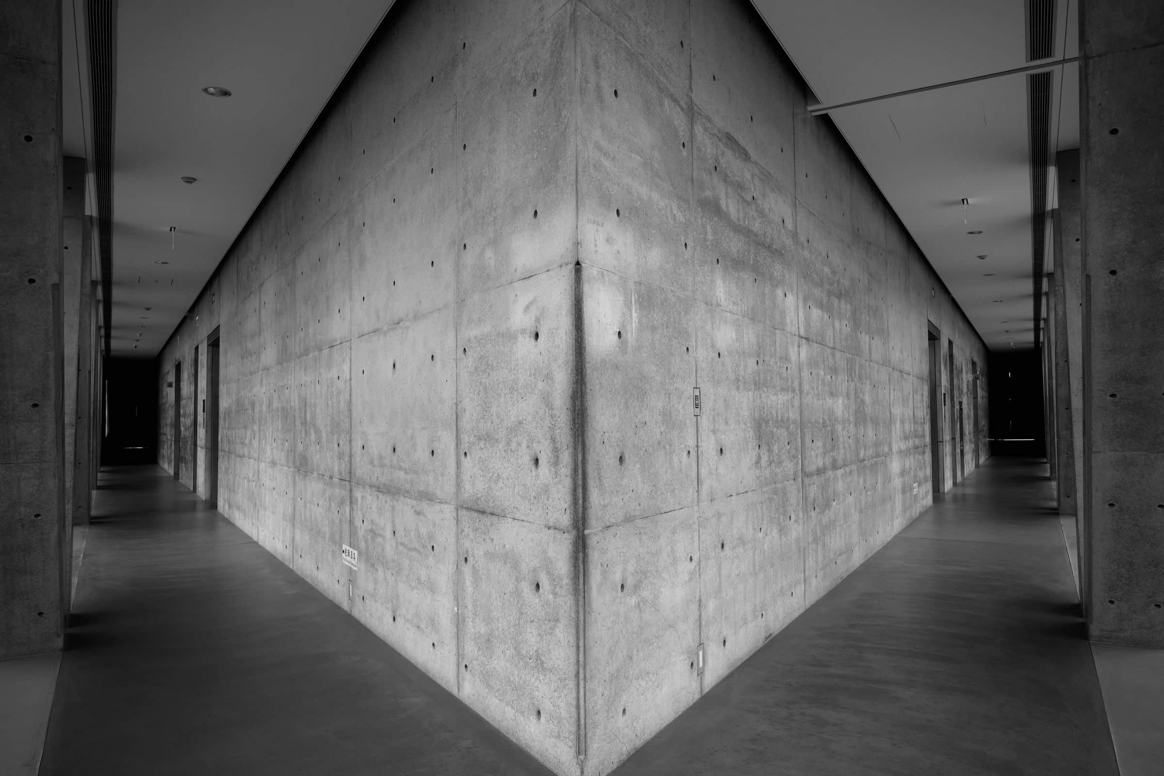Board-formed concrete walls along a softly lit architectural corridor