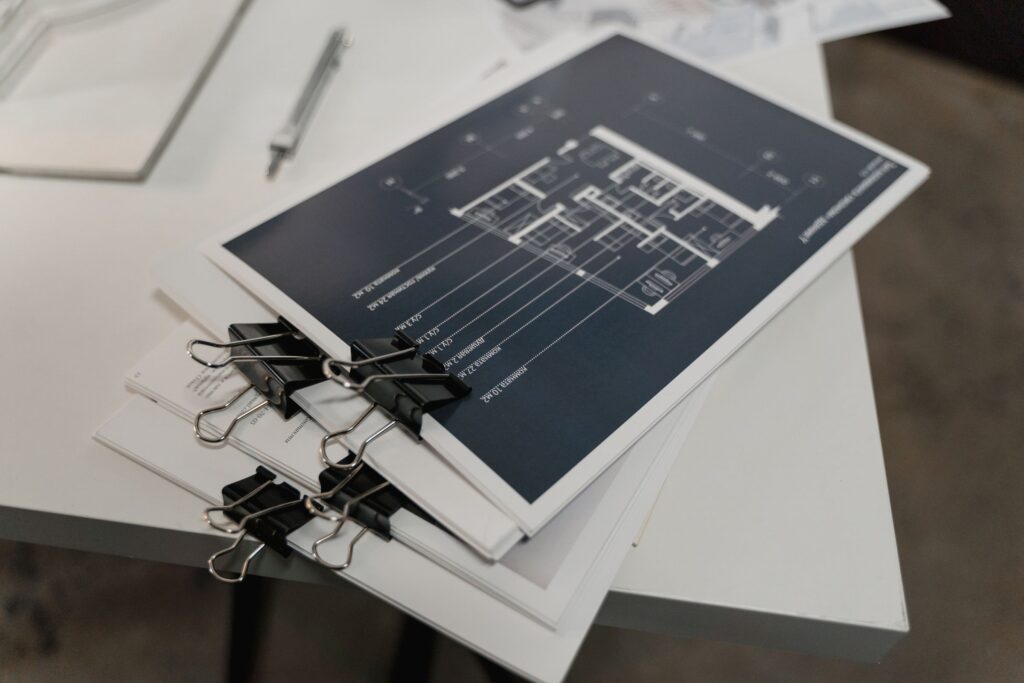 Stack of bound architectural floor plans on a white table