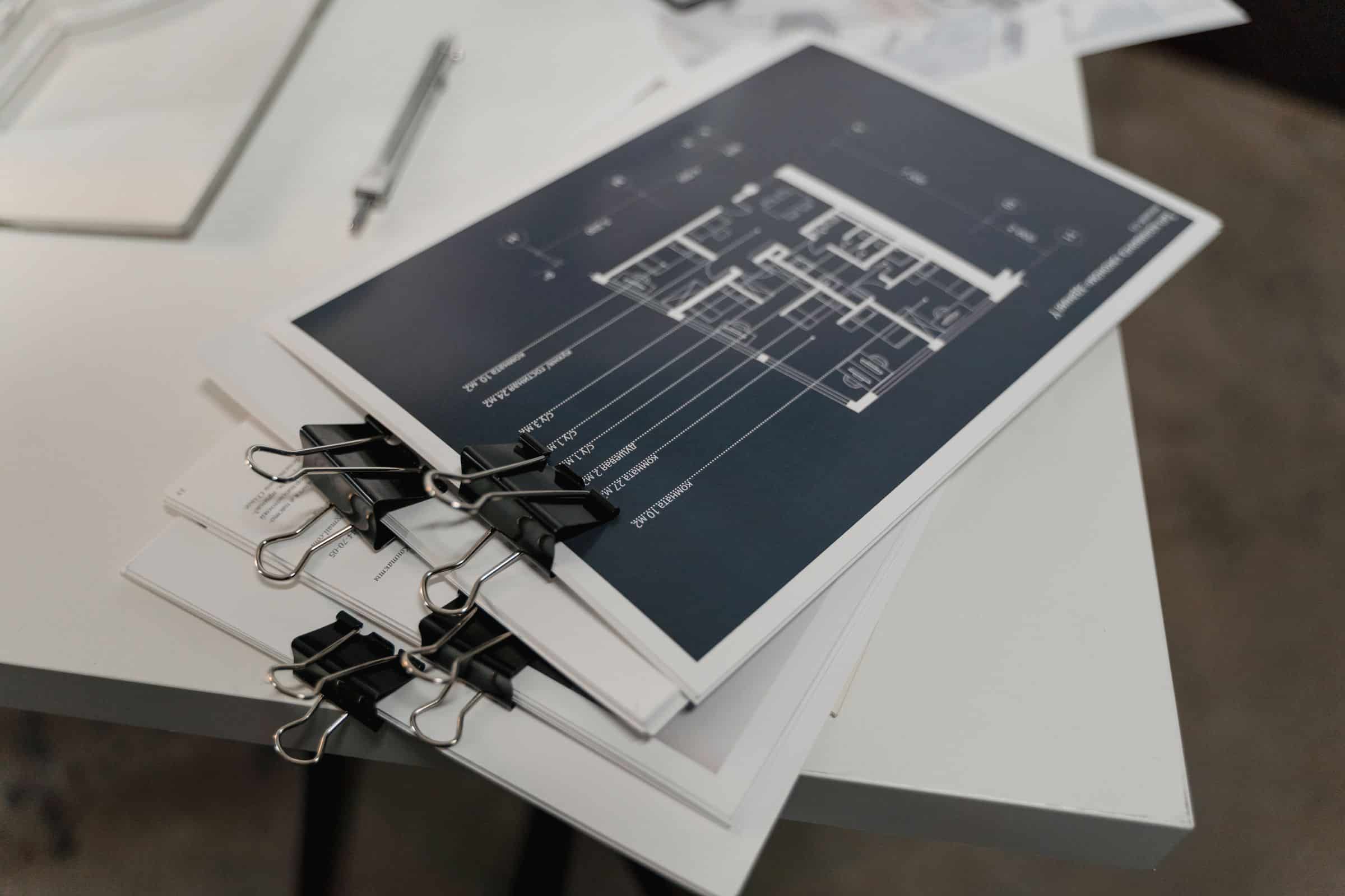 Stack of bound architectural floor plans on a white table