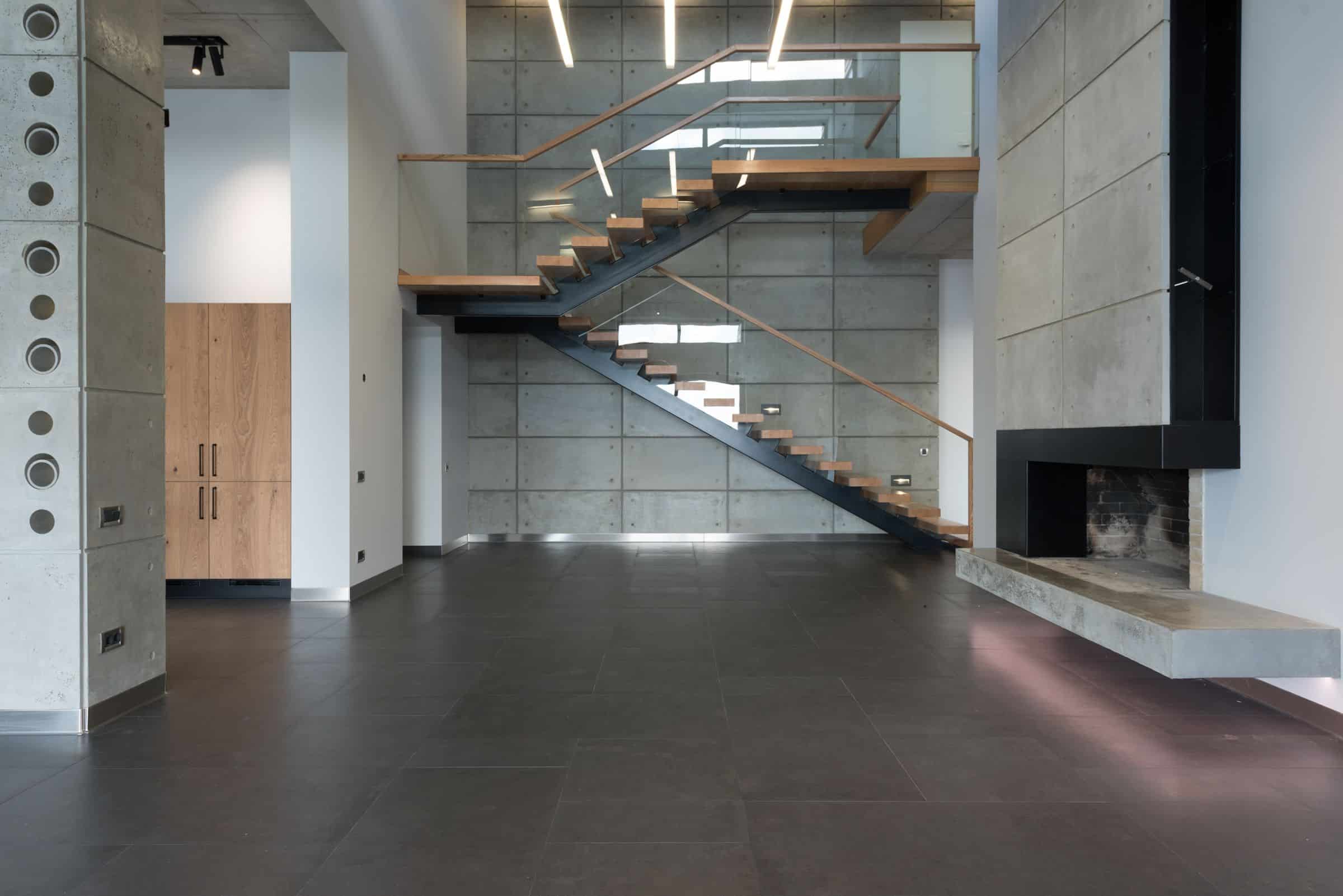 Steel and timber stair detail against a concrete wall in low light