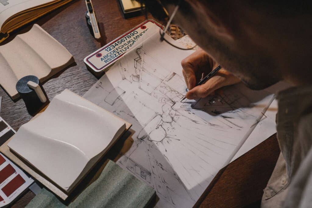 Hands sketching architectural details at a drafting desk