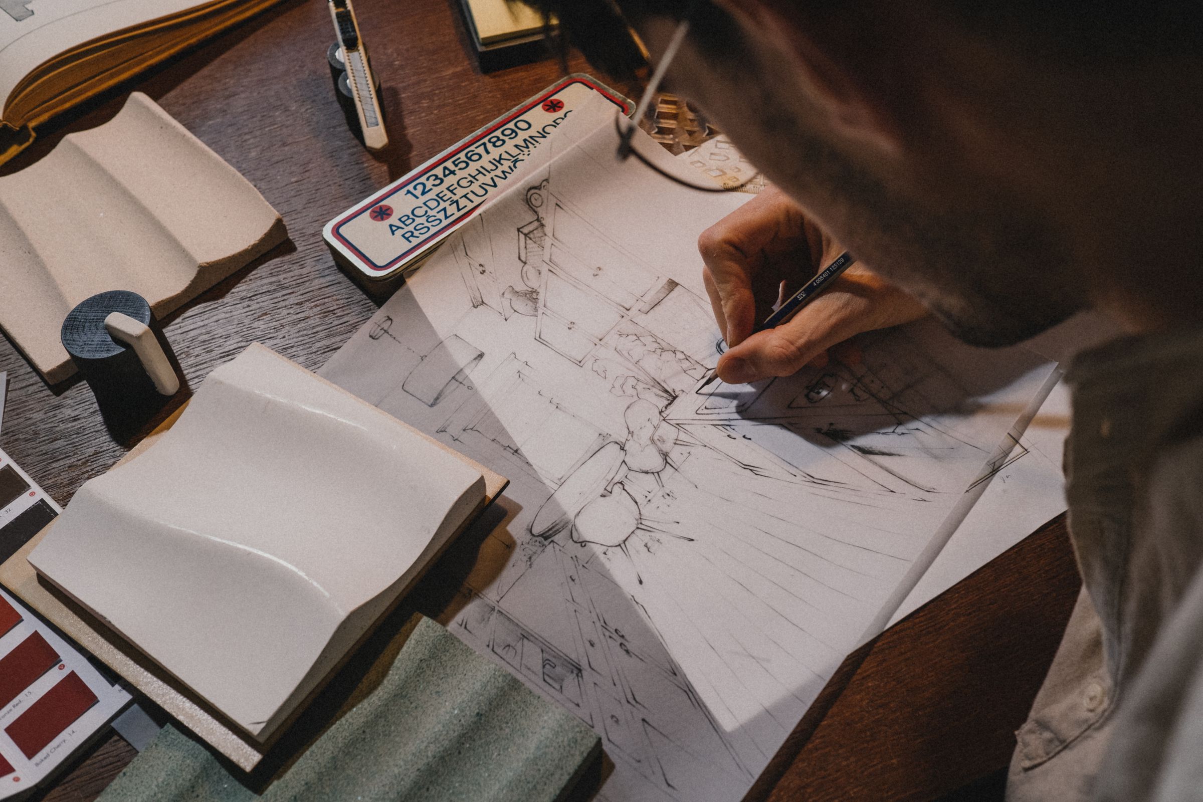 Hands sketching architectural details at a drafting desk
