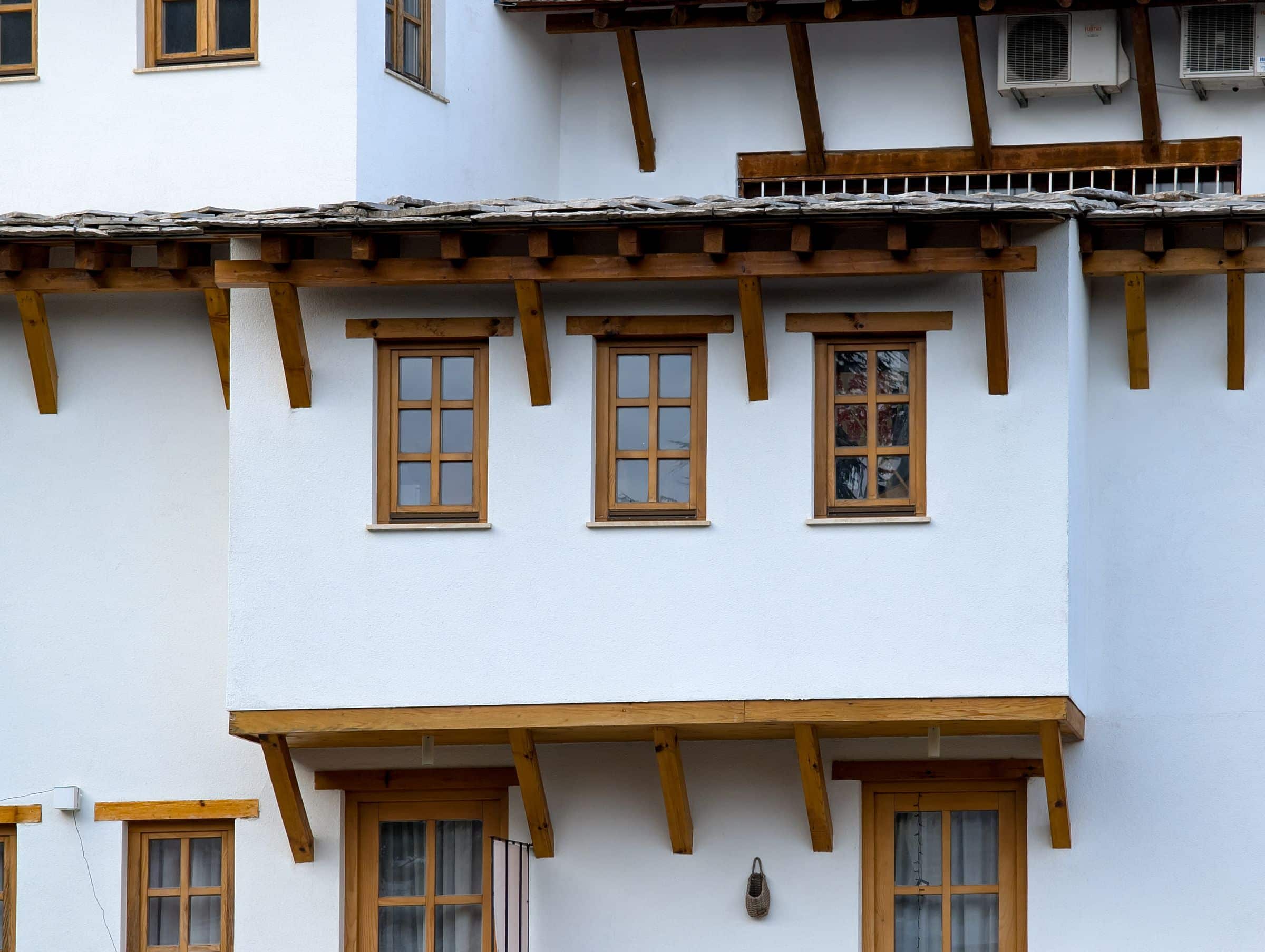 White house exterior with timber-framed windows and a deep eave
