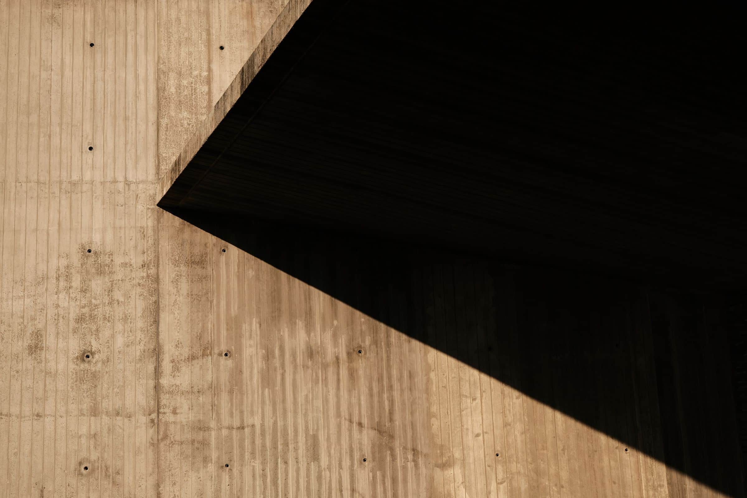 Hard diagonal shadow across a concrete and timber surface