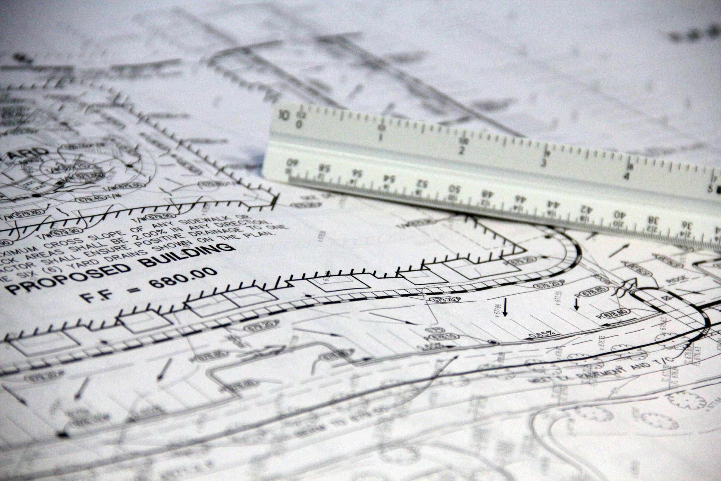 Architectural blueprint drawings with a scale ruler on a drafting surface