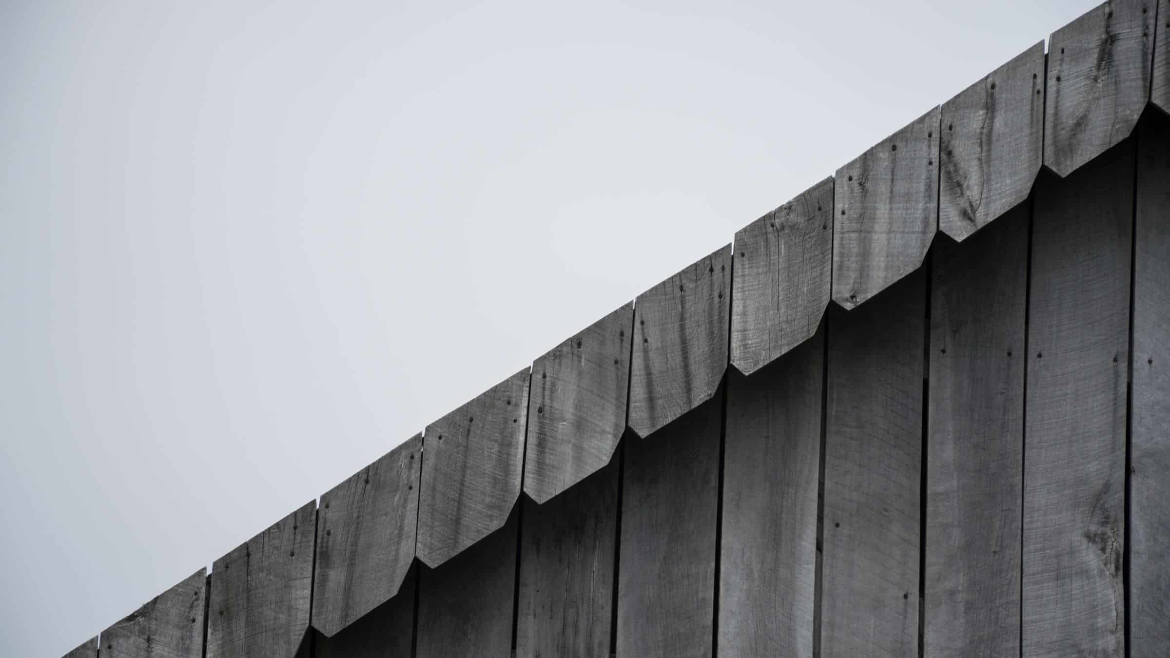Dark timber facade with vertical cladding panels against a pale sky