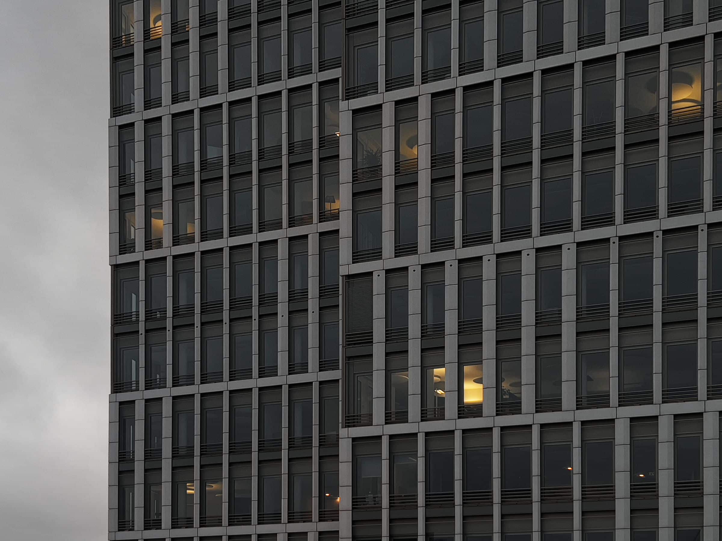 Grid facade of a commercial building with lit windows at dusk