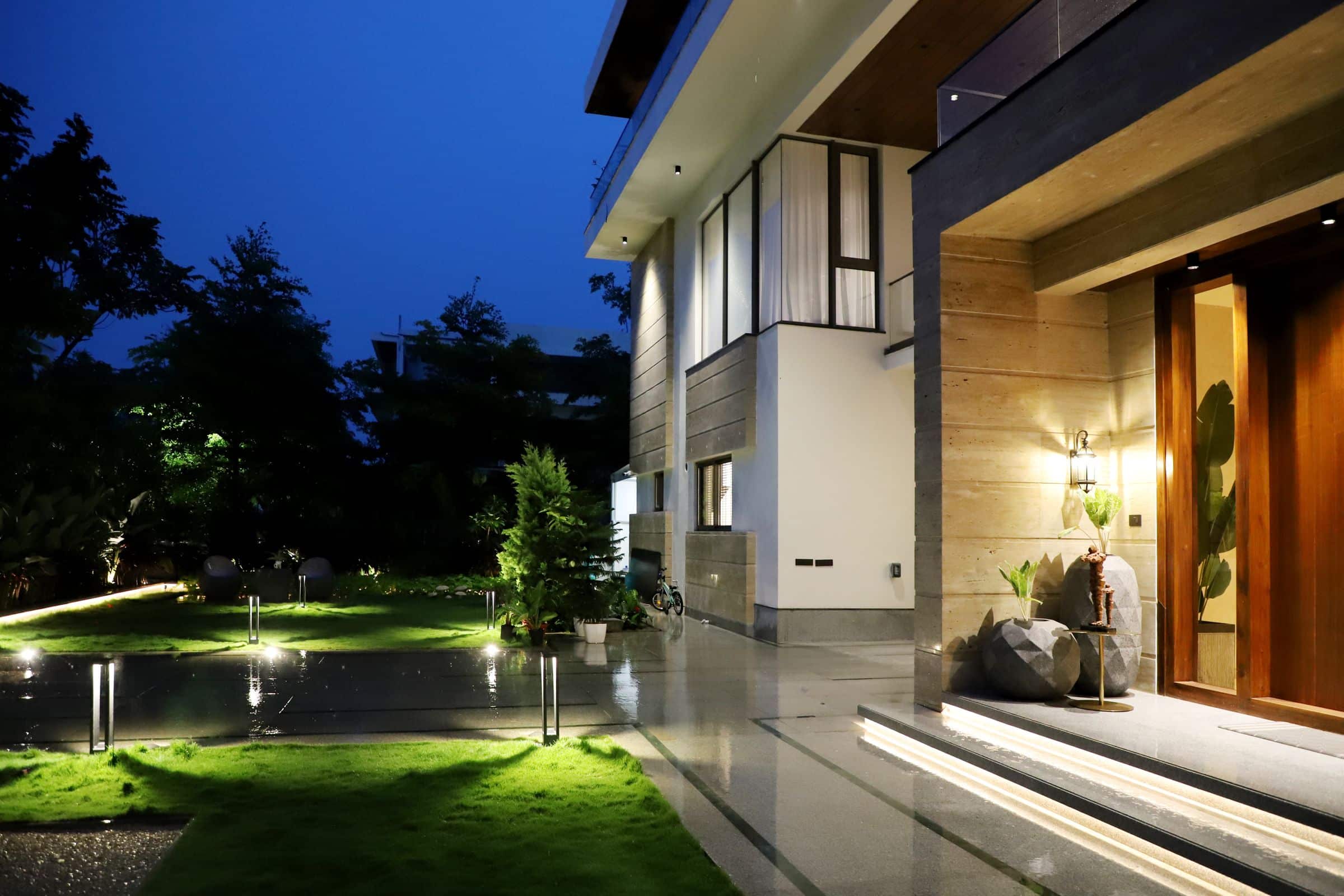 Contemporary residence illuminated at evening with stone cladding and garden lighting