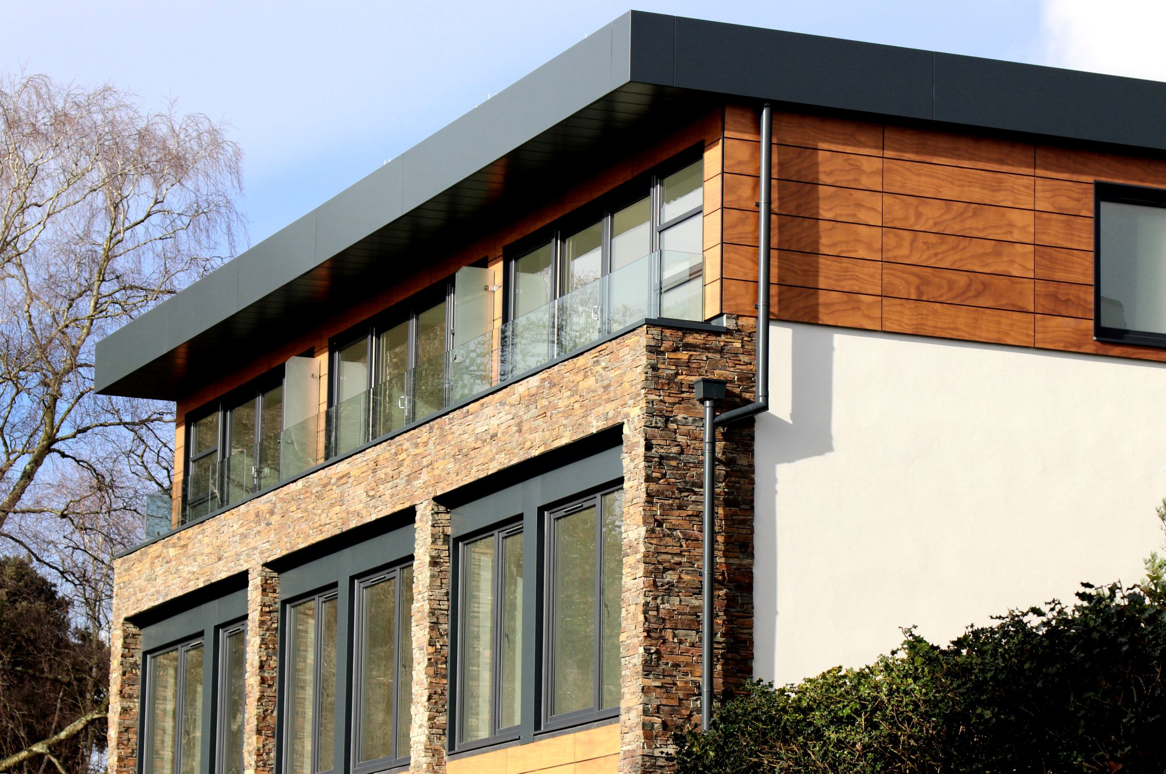 Contemporary residence combining stone, timber and glass in daylight