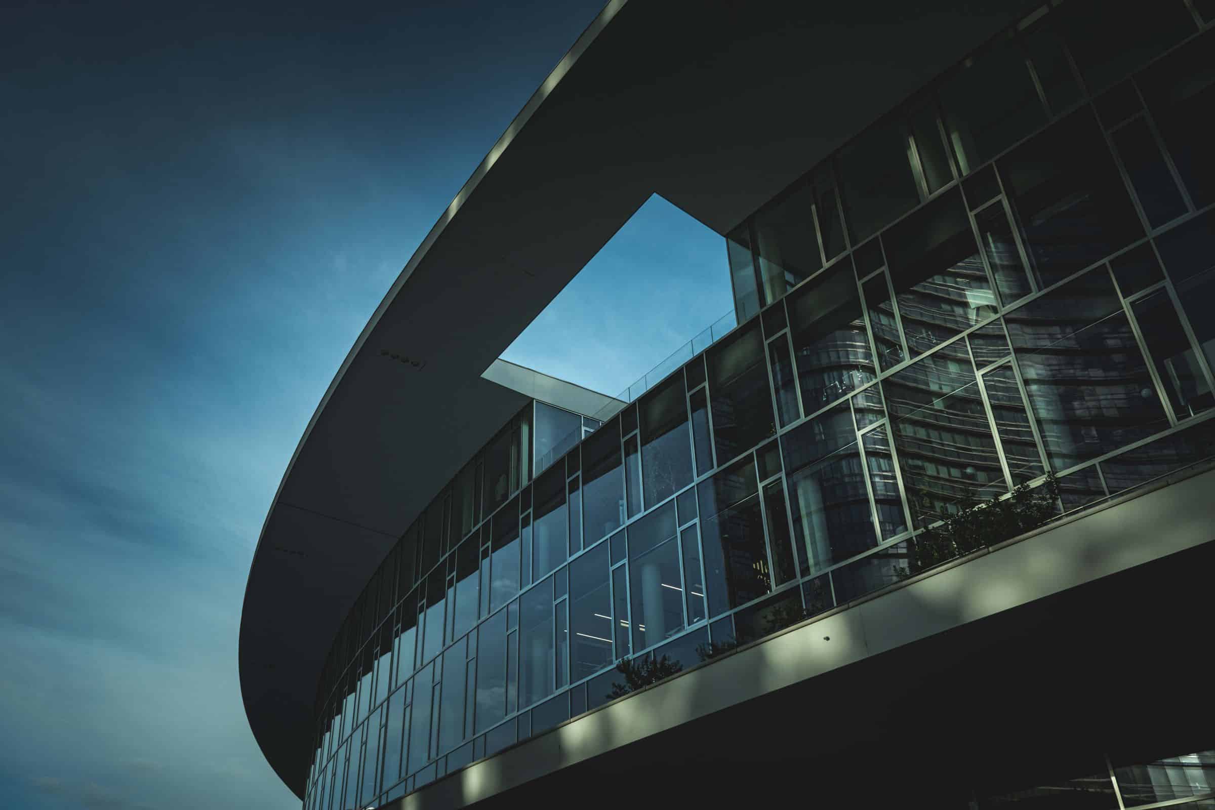 Curved glass commercial building facade viewed from below