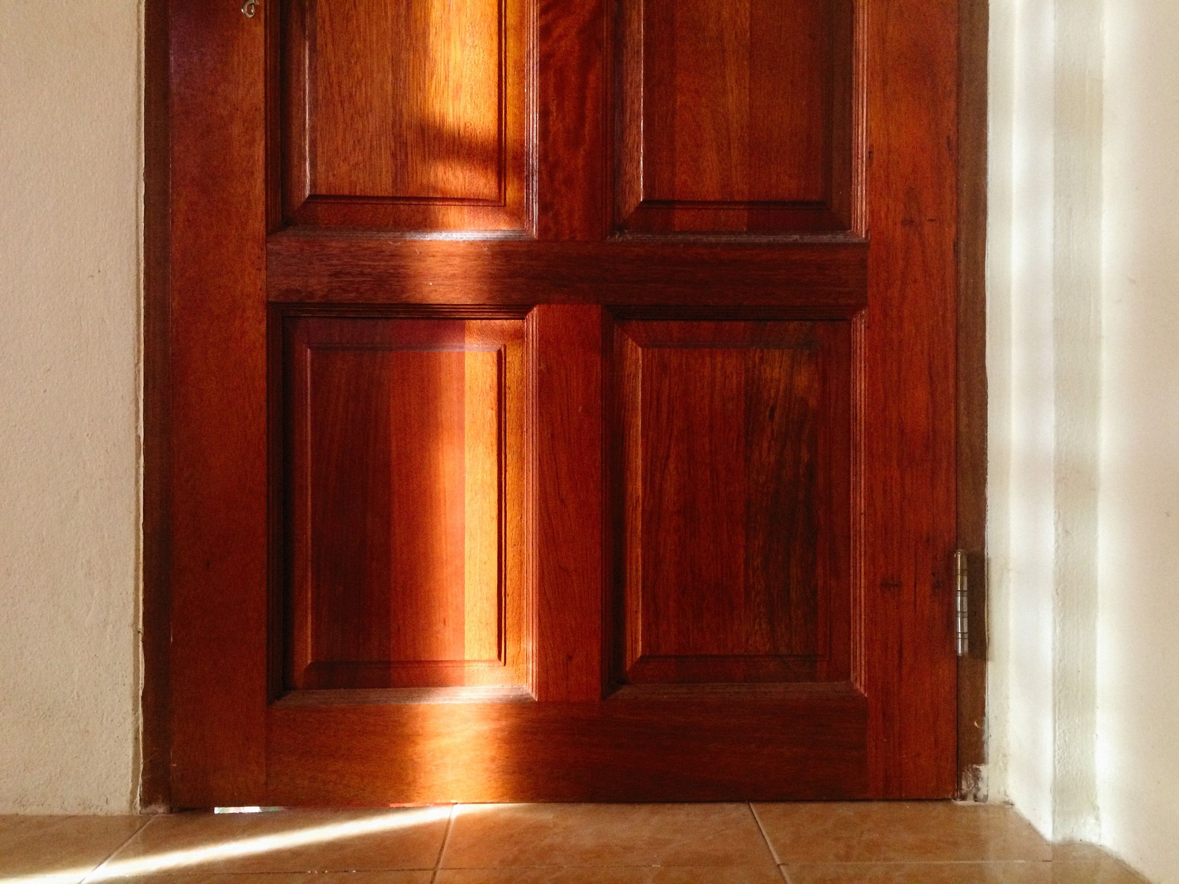 Walnut door with fine joinery and a brass handle in warm light