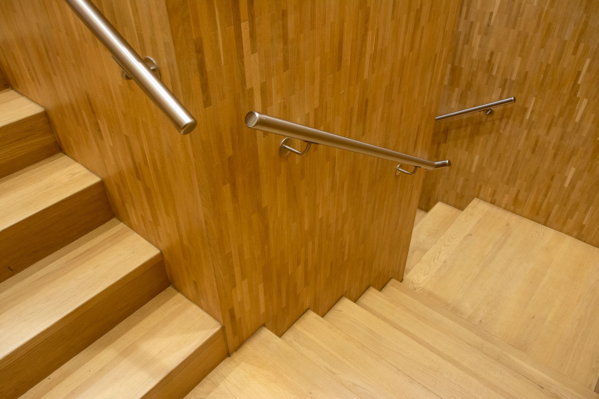Oak staircase with brushed steel handrails and precision-finished timber panelling — representative craftsmanship detail